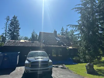 Cedar shake roof being removed around a skylight and chimney above a house and garage.